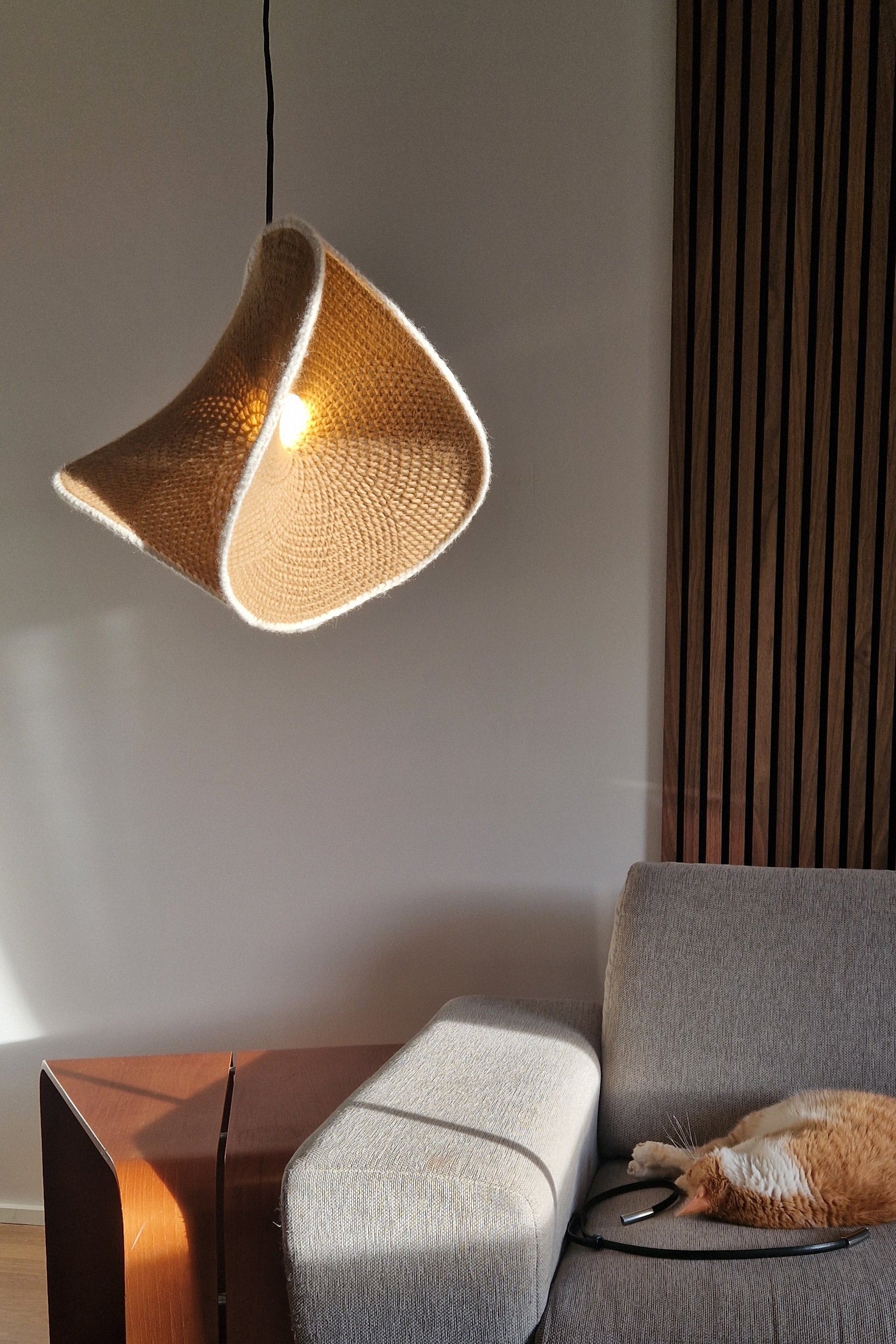 Modern lamp on a white surface with a gray sofa and wooden floor in the background